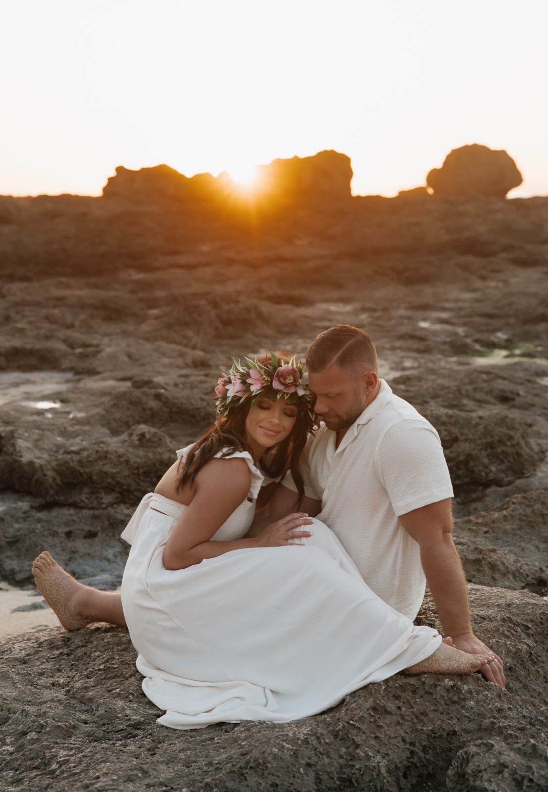 Josh Littauer and Morgan sitting together on the rocks at sunset